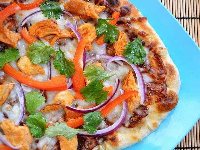 Close-up of Thai chicken pizza topped with herbs.