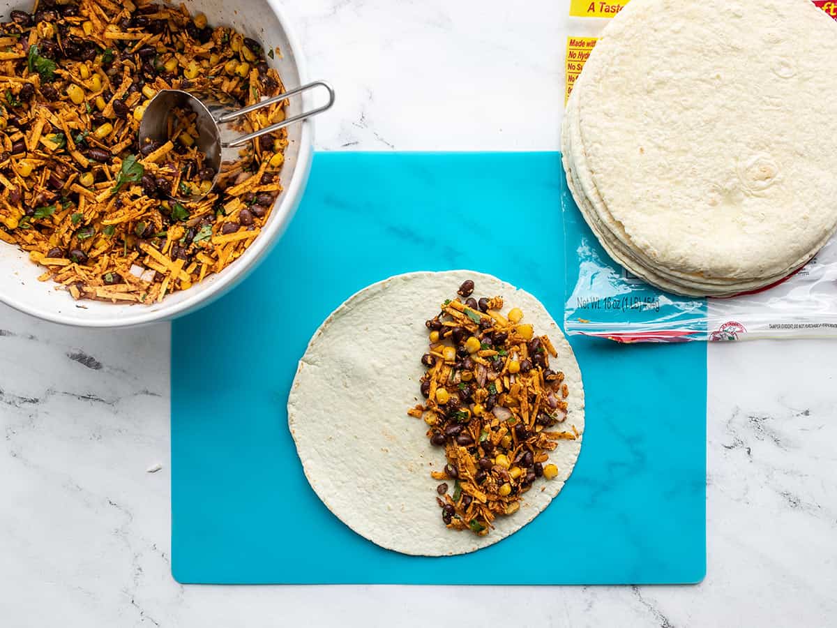 A tortilla being filled with the bean and cheese mixture