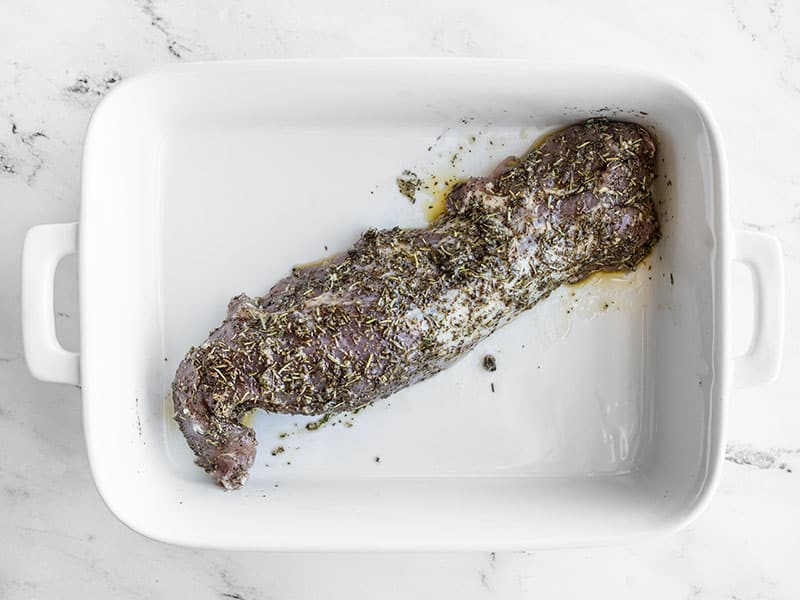 Herb coated pork tenderloin in a baking dish