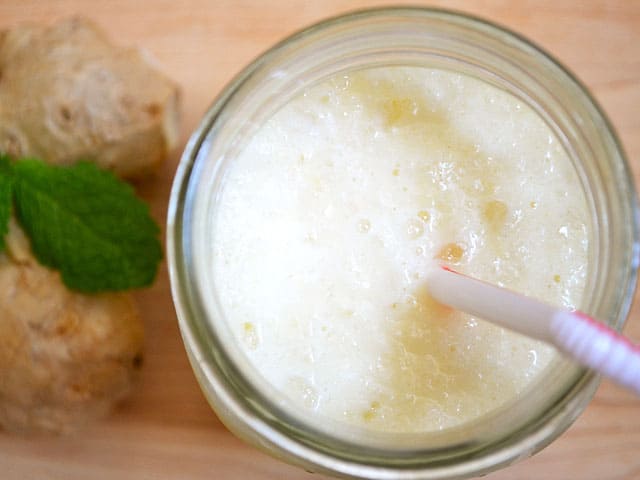 Pineapple ginger lassi in a glass with a straw.