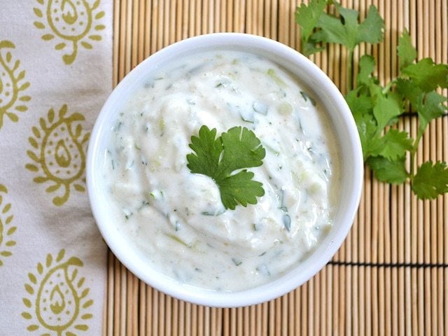 Raita served in a bowl with herbs.