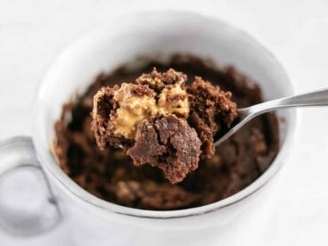 Chocolate cake being lifted out of the mug with a spoon.