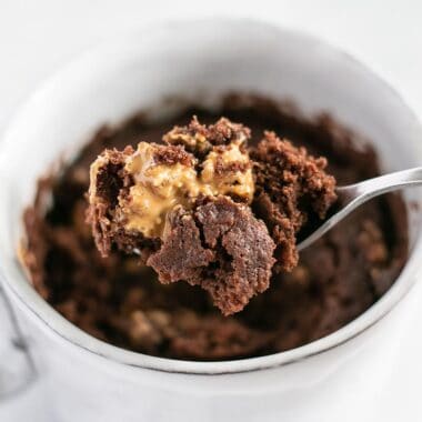 Chocolate cake being lifted out of the mug with a spoon.