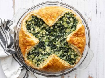 Overhead view of spinach pie in the glass pie dish on a wooden surface