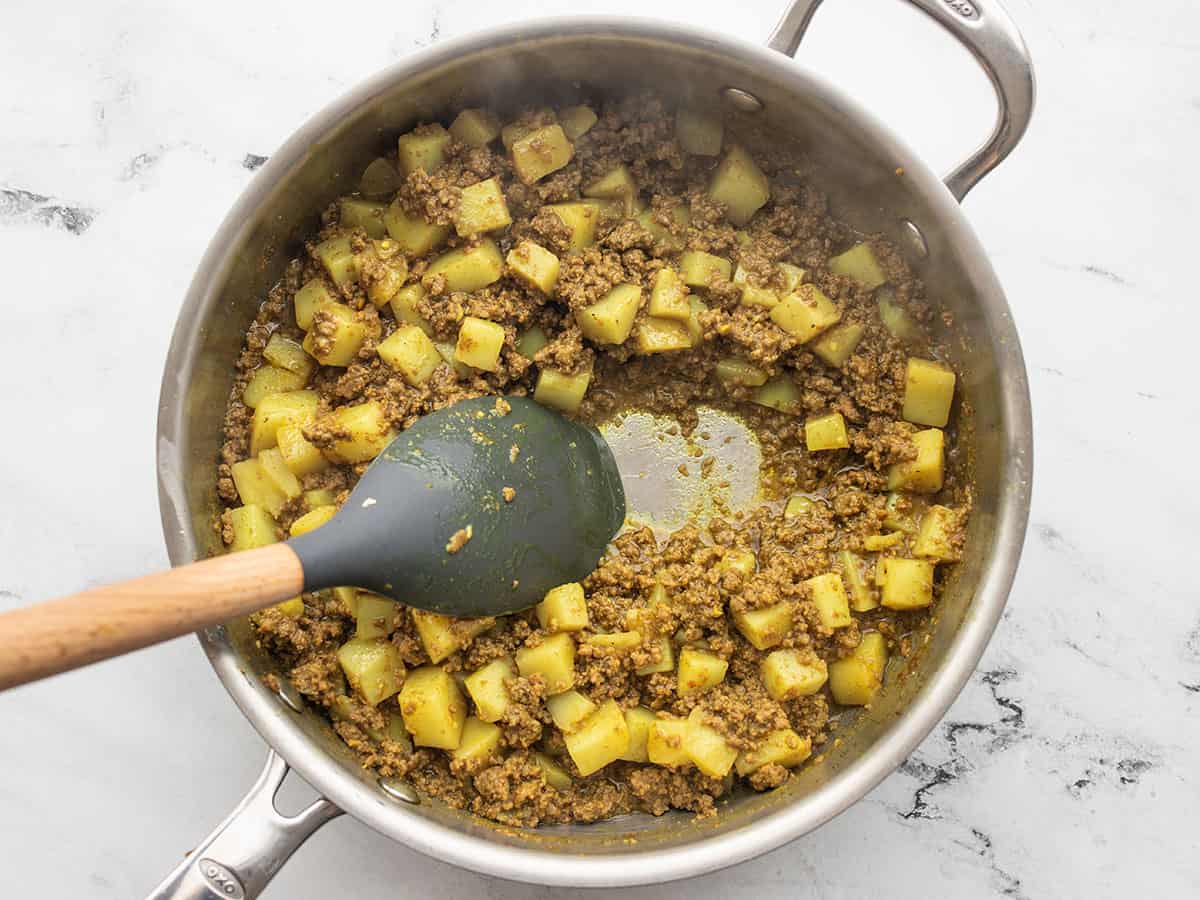 Spatula pulling beef and potatoes to the side to show no liquid in the skillet