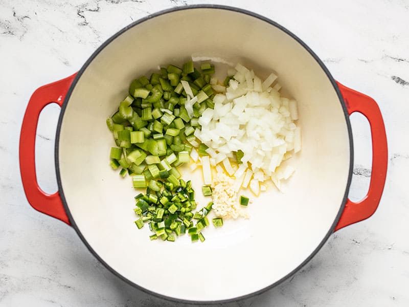 Onion, celery, jalapeño, and garlic in soup pot with olive oil