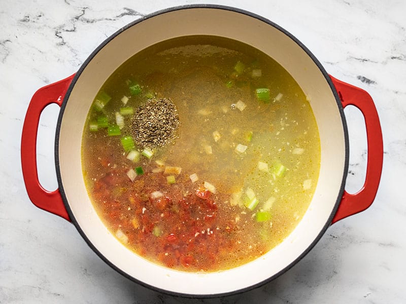 Add cumin and oregano to the soup pot.