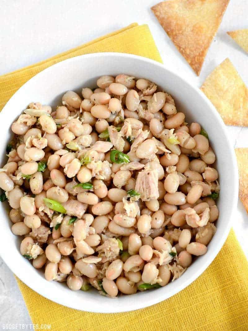 top view of a bowl of tuna and white bean salad with pita chips on the side 