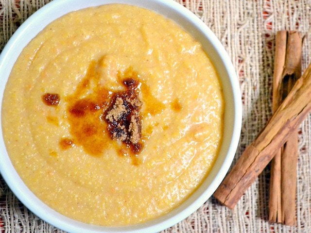 Close-up of sweet potato grits in a bowl alongside cinnamon sticks.