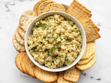 Pesto chickpea salad in a bowl surrounded by crackers