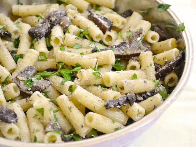 A bowl of portabella pasta garnished with herbs.