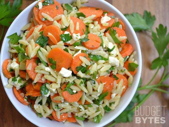 Carrot and orzo salad garnished with herbs.