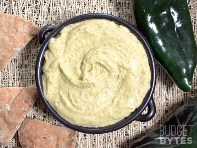 Top view of a bowl of Roasted Poblano Hummus with chips on the side 