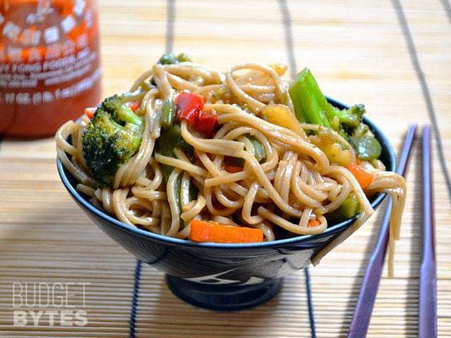 Teriyaki noodle bowl with vegetables and chicken along with chopsticks.