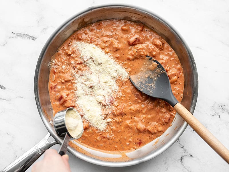 Parmesan cheese being sprinkled into the skillet