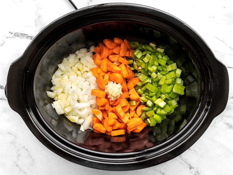 Chopped celery, carrot, onion, and garlic in the slow cooker