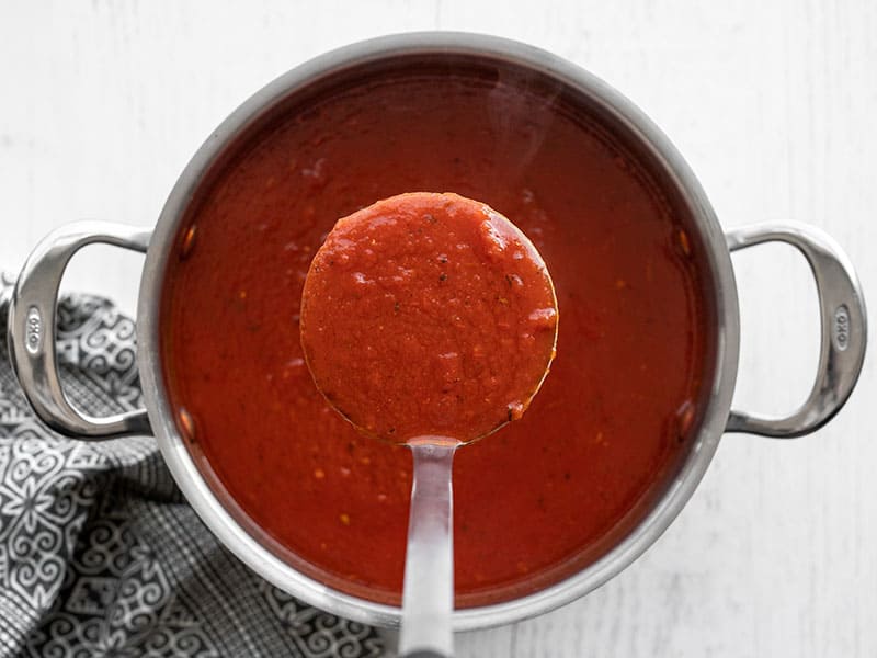 finished tomato herb soup being lifted with a ladle 