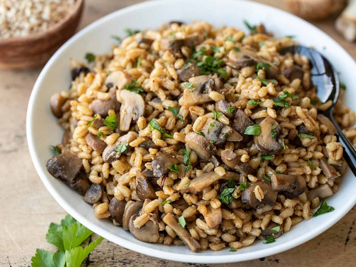 Side view of a serving dish full of baked barley with mushrooms