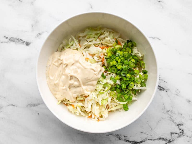 Coleslaw mix with green onions and dressing in a bowl