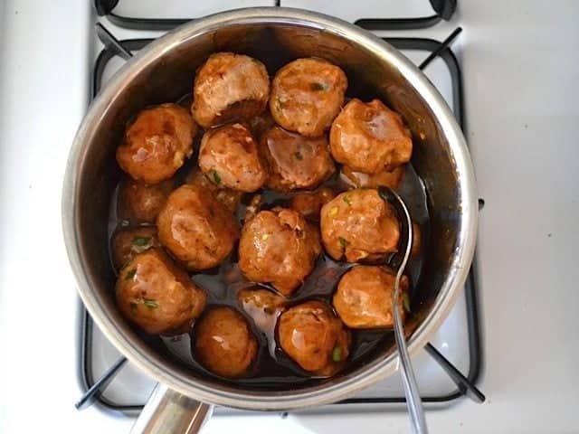 Cooked Meatballs added to pot of glaze on stovetop 