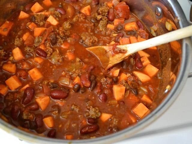 Top view of finished chili in pot with wooden spoon 