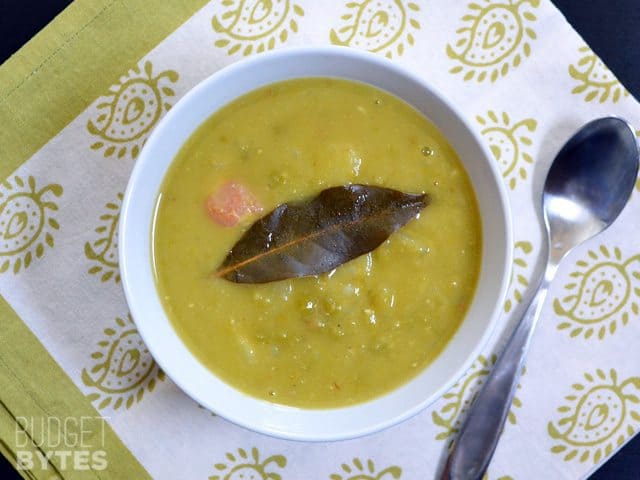 Top view of a bowl of Split Pea Bacon & Potato Soup with a spoon on the side 