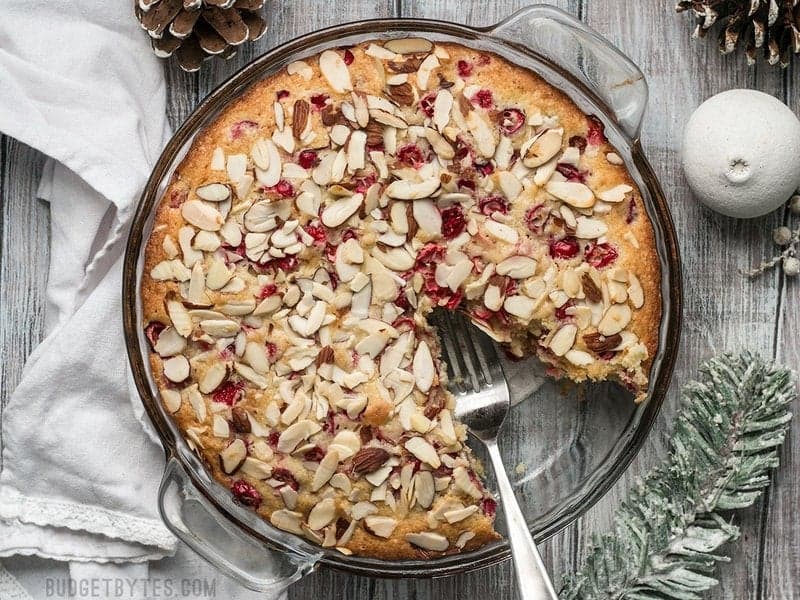 Top view of baked Cranberry Almond Cake with one slice removed 