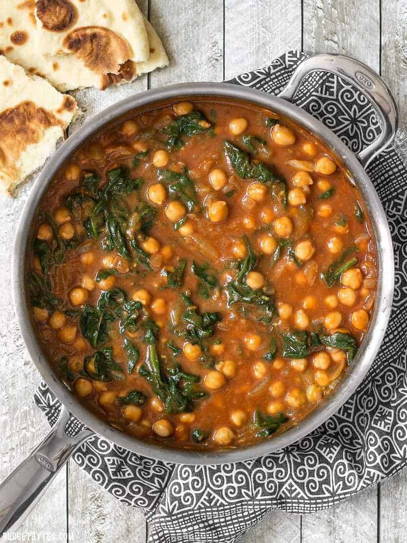 Skillet full of Curried Chickpeas with Spinach and Naan bread on the side.