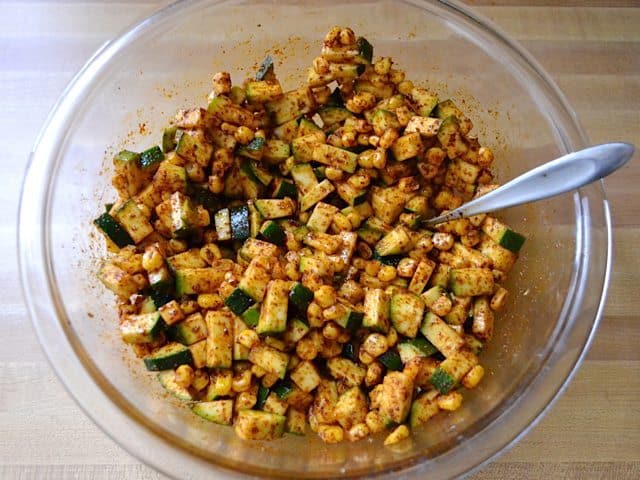 Veggies stirred with seasoning in mixing bowl 