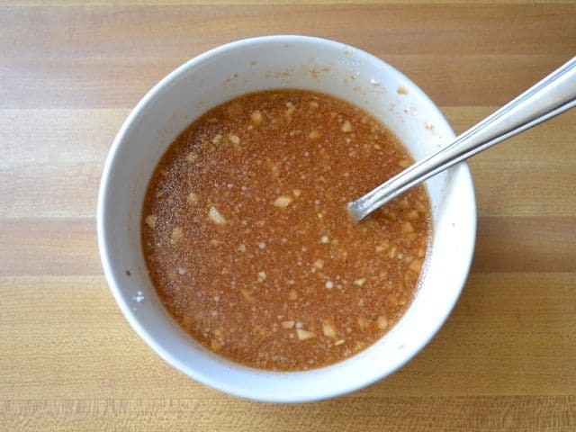 Corn Starch added to marinade ingredients in small mixing bowl with fork 