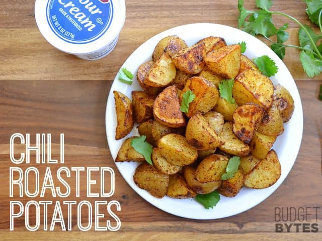 Top view of a bowl of Chili Roasted Potatoes with sour cream on the side 