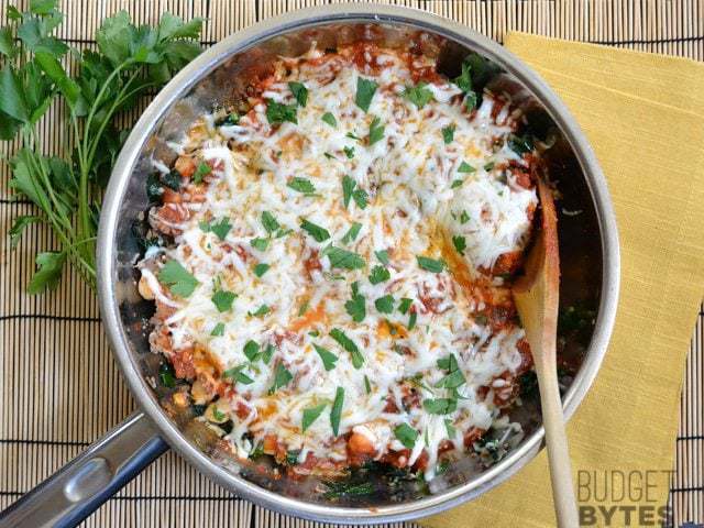 A skillet of kale and sausage dish served hot.