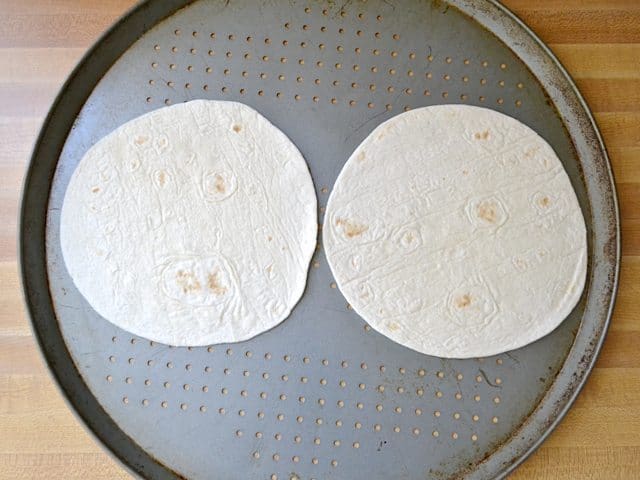 Two tortillas placed on pizza pan 