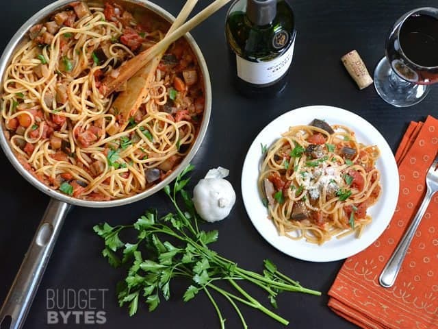 Top view of a skillet of Pasta with Eggplant Sauce and a small plate with a serving on it 