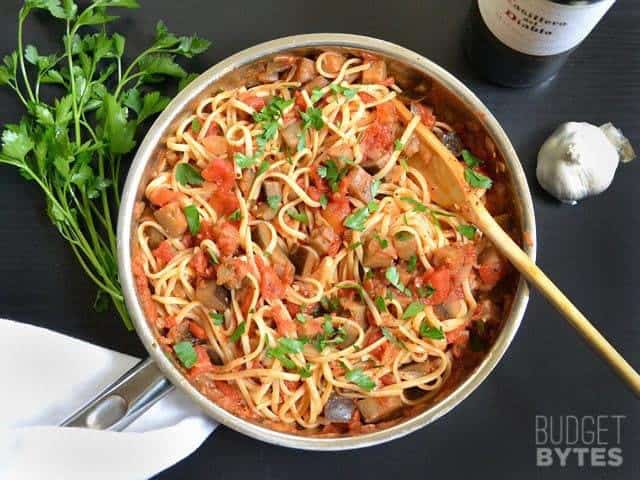 A skillet of pasta topped with eggplant sauce.