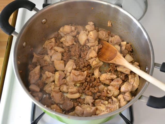 Browned Meat (chicken and chorizo) in pot with wooden spoon 