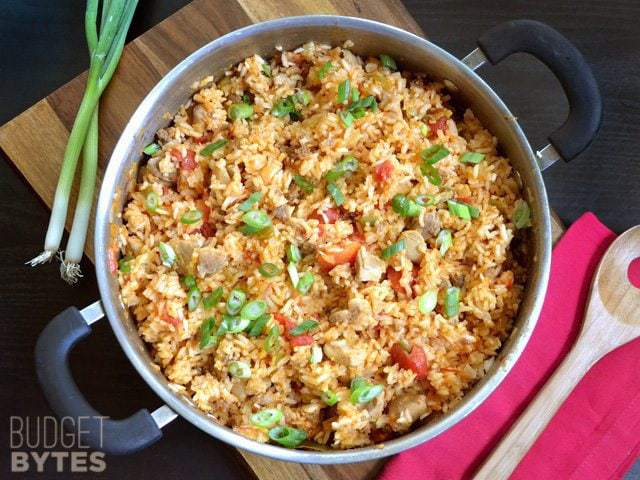 A pot of chorizo chicken jambalaya garnished with herbs.