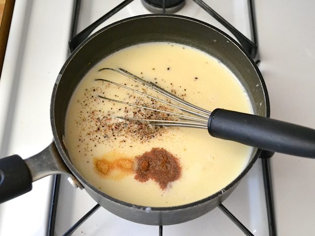 Milk and seasoning added to other sauce ingredients in pan and whisked in 