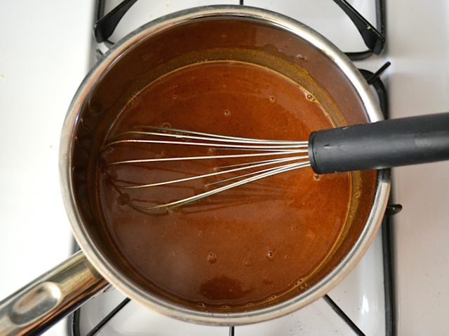 Water added to other ingredients for enchilada sauce in pot 