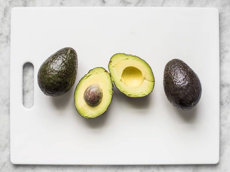 Three avocados, one cut in half 