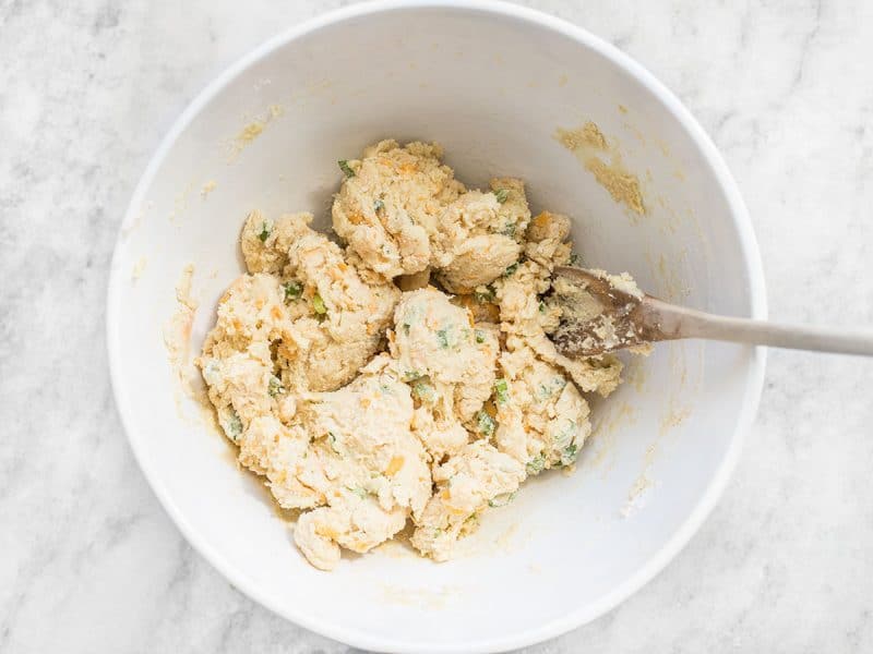 Cheddar Scallion Scone Dough in mixing bowl with wooden spoon 