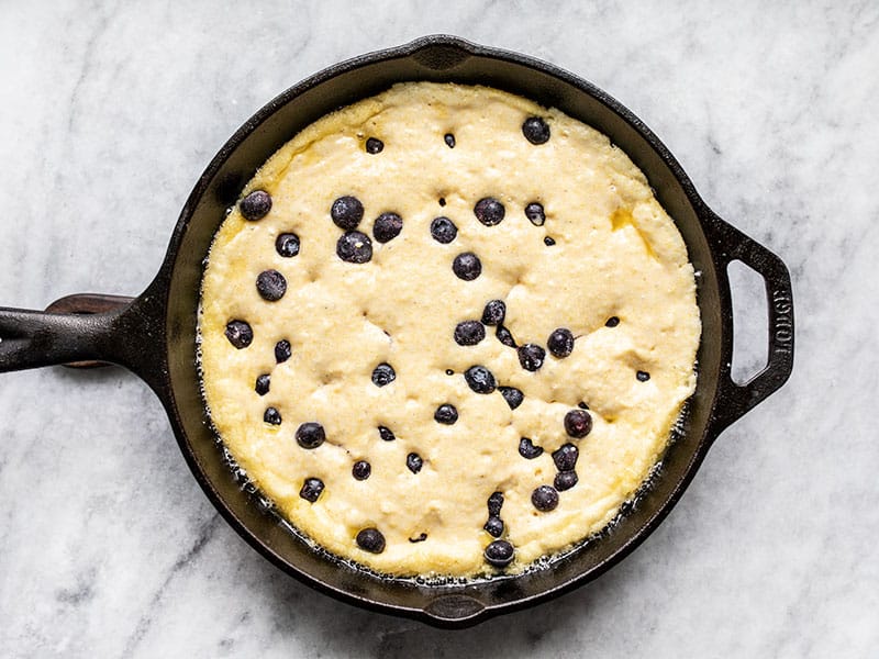 Batter and blueberries in hot skillet ready to bake.