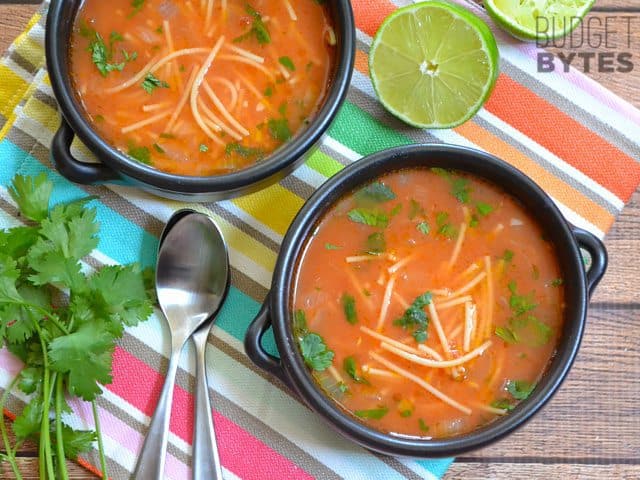 Top view of two bowls of Sopa de Fideo with two spoons, cilantro and napkins on the side 