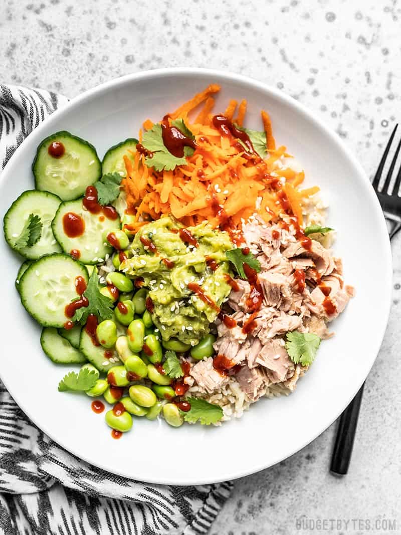 Overhead view of a Spicy Tuna Guacamole Bowl with sriracha and sesame seeds sprinkled over top.