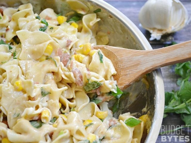 Scoop of Creamy Vegetarian Enchilada Pasta being scooped out with wooden spoon 