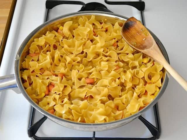 Uncooked egg noodles and broth added to skillet 