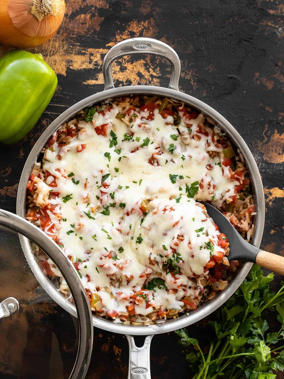 Overhead view of unstuffed bell peppers in the skillet with a spoon.