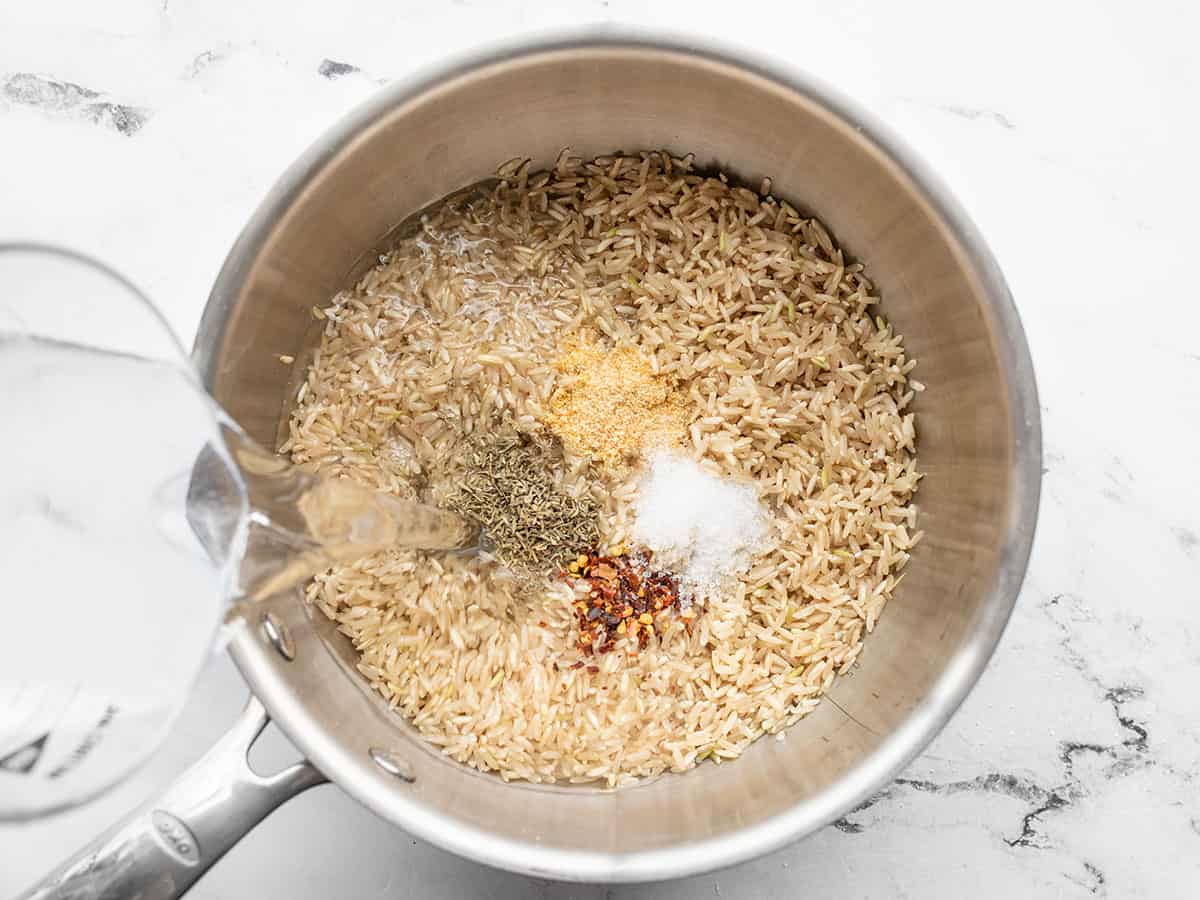 Water being poured into the pot with rice and seasonings