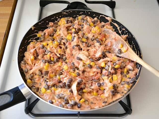 Enchilada filling stirred together in skillet on stove top 