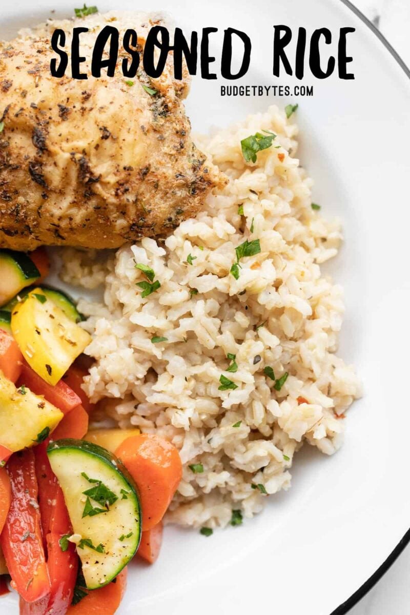 Overhead view of seasoned rice on a plate with vegetables and chicken